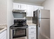 Thumbnail 19 of 24 - A kitchen with a stove, refrigerator, and cabinets.