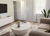 Thumbnail 15 of 24 - A living room with a white couch, a coffee table, and a flat screen TV.
