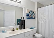 Thumbnail 11 of 42 - A bathroom with a white toilet, sink, and shower curtain.