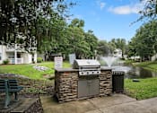 Thumbnail 29 of 42 - A BBQ grill is in the middle of a grassy area with a sign in front of it.