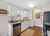 Thumbnail 4 of 42 - A small, clean, and well-equipped kitchen with white cabinets and stainless steel appliances.