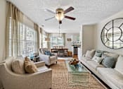 Thumbnail 7 of 42 - A living room with a beige couch, a glass coffee table, and a ceiling fan.
