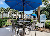 Thumbnail 25 of 42 - A blue umbrella is over a table with chairs around it.