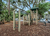 Thumbnail 32 of 42 - A playground with a wooden swing set and a green canopy.