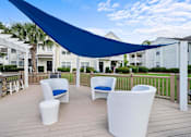 Thumbnail 26 of 42 - A blue shade sail over a white patio furniture set.