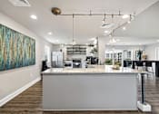 Thumbnail 14 of 42 - A modern kitchen with a large island and a painting on the wall.