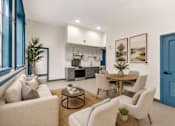 Thumbnail 1 of 7 - A modern living room with a dining area and kitchen in the background.