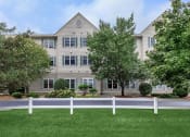 Thumbnail 10 of 57 - an exterior view of an apartment building with a white fence
