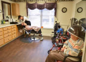 Thumbnail 40 of 57 - a patient sits in a chair while a woman cuts his hair in a patient room