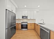 Thumbnail 11 of 11 - A modern kitchen with wooden floors and stainless steel appliances.