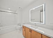 Thumbnail 3 of 11 - A white bathroom with a toilet, sink, and mirror.