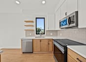 Thumbnail 9 of 11 - A kitchen with a dishwasher, microwave, and a window.