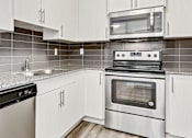 Thumbnail 9 of 44 - a kitchen with white cabinets and stainless steel appliances