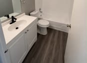 Thumbnail 10 of 11 - A white toilet sits in a bathroom next to a sink and mirror.