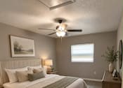 Thumbnail 5 of 11 - A bedroom with a bed, a ceiling fan, and a window.