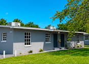Thumbnail 2 of 11 - A grey house with a tree in front.
