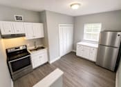 Thumbnail 8 of 11 - A kitchen with a stove, sink, and refrigerator.
