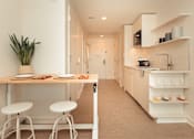 Thumbnail 18 of 36 - a small kitchen with a table and stools at Scout Living, powered by Placemakr Apartments, Atlanta, 30308