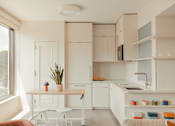 Thumbnail 19 of 36 - a small kitchen with white cabinets and a table and chairs at Scout Living, powered by Placemakr Apartments, Atlanta, GA, 30308