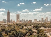 Thumbnail 36 of 36 - the skyline of the city with a blue cloudy sky and trees at Scout Living, powered by Placemakr Apartments, Atlanta, 30308