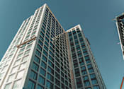 Thumbnail 26 of 36 - looking up at two tall skyscrapers with a blue sky behind them at Scout Living, powered by Placemakr Apartments, Atlanta, GA