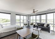 Thumbnail 2 of 23 - A modern bedroom with a large bed and a spacious living area with a couch and chairs at Anthem House Apartment , Huntsville, AL