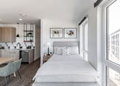 Thumbnail 6 of 23 - A modern bedroom with a large bed and a kitchen area in the background at Anthem House Apartment , Alabama, 35806