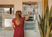 Thumbnail 20 of 36 - a woman is standing in front of an open refrigerator at Scout Living, powered by Placemakr Apartments, Georgia