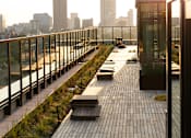 Thumbnail 32 of 36 - a rooftop deck with benches and a city skyline in the background at Scout Living, powered by Placemakr Apartments, Georgia 30308