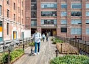 Thumbnail 30 of 36 - people walking on a boardwalk in front of a building at Scout Living, powered by Placemakr Apartments, Atlanta, Georgia