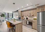 Thumbnail 22 of 28 - A modern kitchen with wooden cabinets and stainless steel appliances at Coda on Half Apartments, Washington, DC 20003