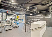 Thumbnail 19 of 28 - A gym with treadmills and a motivational quote on the wall at Coda on Half Apartments, Washington