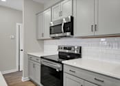 Thumbnail 7 of 36 - an empty kitchen with white cabinets and a stove and microwave