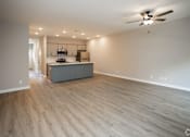 Thumbnail 24 of 36 - an empty living room with a kitchen and a ceiling fan