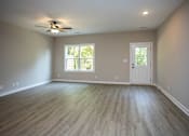 Thumbnail 26 of 36 - an empty living room with wood floors and a ceiling fan