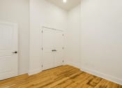 Thumbnail 11 of 19 - a bedroom with two doors and a hardwood floor