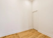 Thumbnail 2 of 19 - a bedroom with white walls and a wooden floor