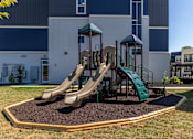 Thumbnail 35 of 39 - A playground with a green slide and a brown sandbox.