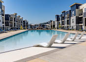 Thumbnail 38 of 39 - A swimming pool surrounded by sun loungers and apartment buildings.