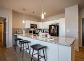 Thumbnail 13 of 39 - A kitchen with a granite countertop and white cabinets.