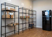 Thumbnail 18 of 39 - A room with shelving units and a black fridge.