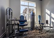 Thumbnail 15 of 39 - A gym room with a rowing machine, a bench, and a chair.