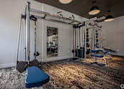 Thumbnail 20 of 39 - A home gym with a blue bench, a mirror, and various exercise equipment.