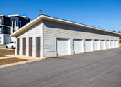 Thumbnail 9 of 39 - A long building with a grey roof and white garage doors.