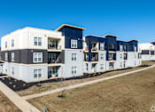 Thumbnail 7 of 39 - A row of modern townhouses with balconies and a clear blue sky above.