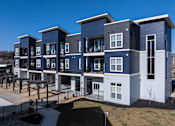 Thumbnail 5 of 39 - A modern apartment complex with multiple balconies and a mix of blue and grey exterior.