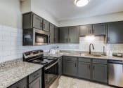 Thumbnail 13 of 23 - a kitchen with granite counter tops and black appliances
