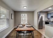 Thumbnail 14 of 23 - a dining room with a wooden table and chairs and a kitchen with stainless steel appliances