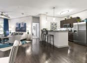 Thumbnail 2 of 14 - a living room and kitchen area with white walls and wood flooring