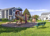 Thumbnail 32 of 42 - a playground with a slide and a bench in front of a building